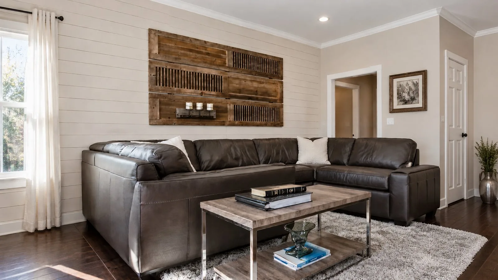 Den with a shiplap wall, a leather sectional and a rustic wooden art panel