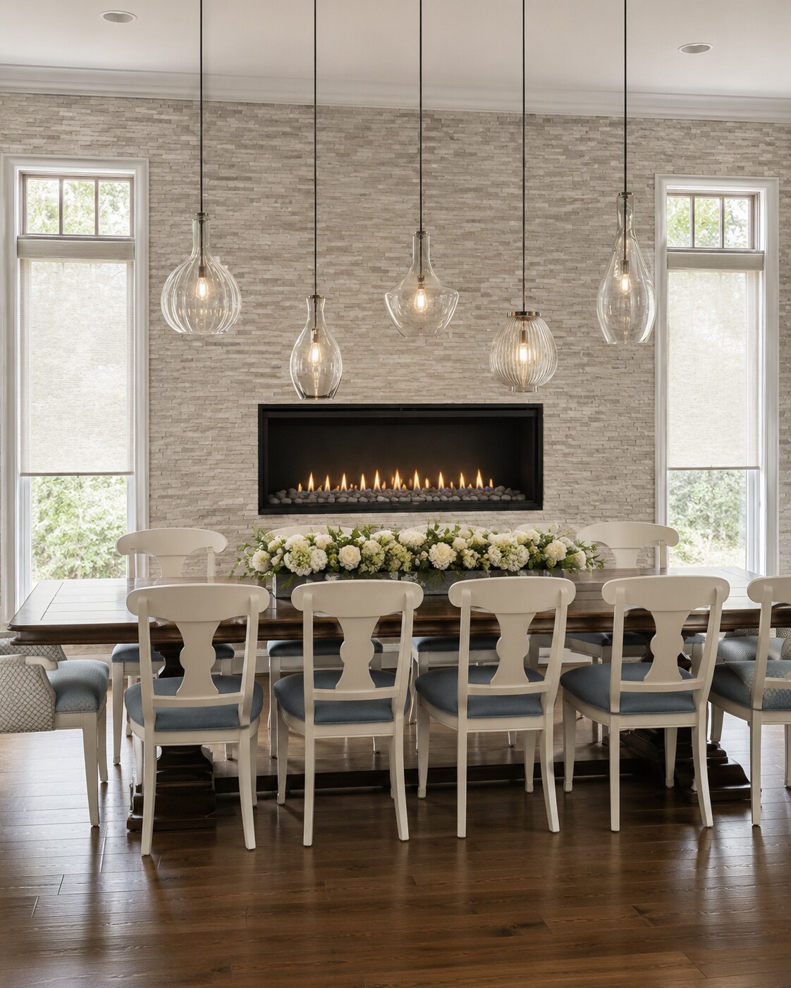 Lakehouse dining space with clustered glass pendants, a linear fireplace, and a stone accent wall