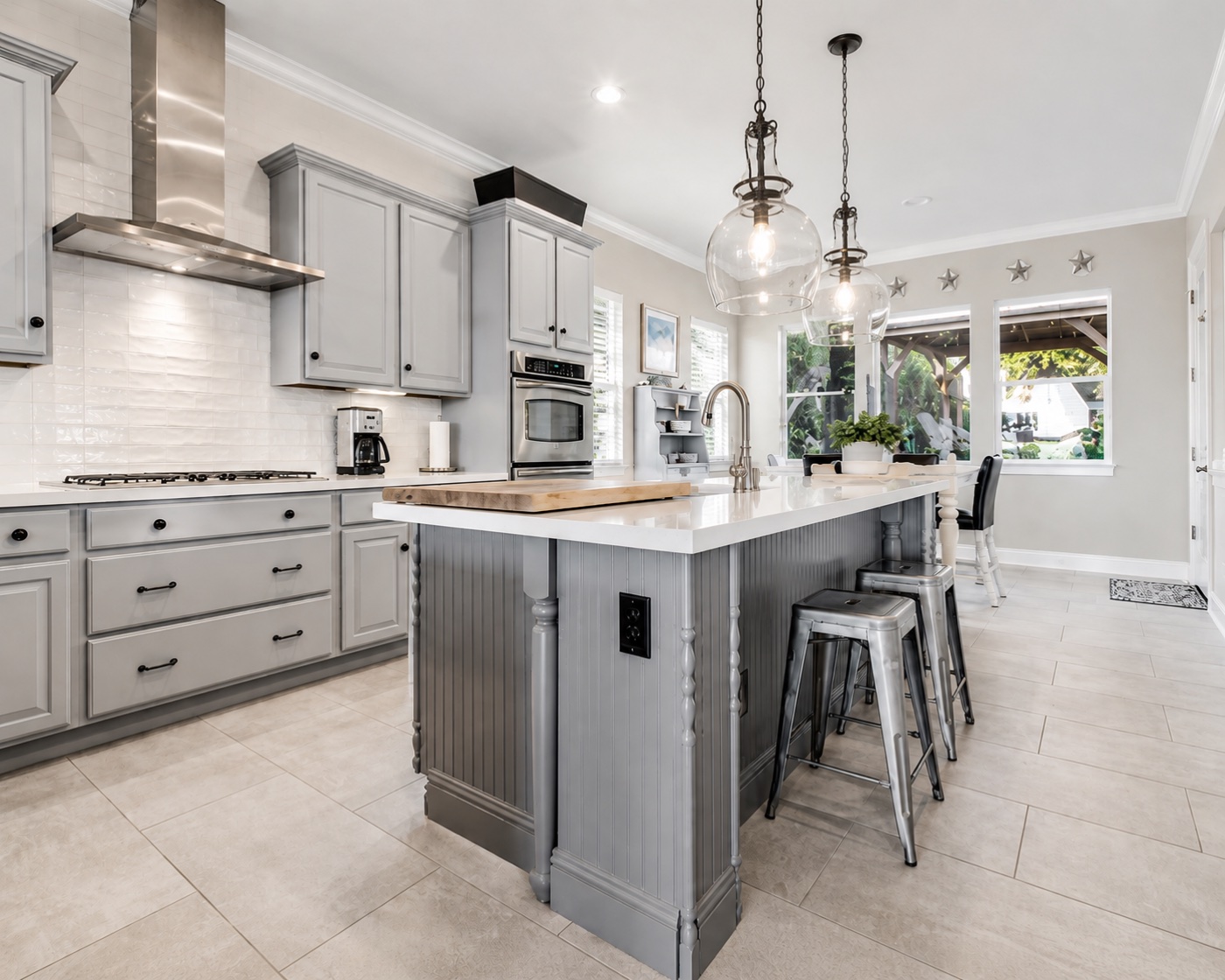 Soft gray kitchen with white counters, glass pendants, and stainless appliances
