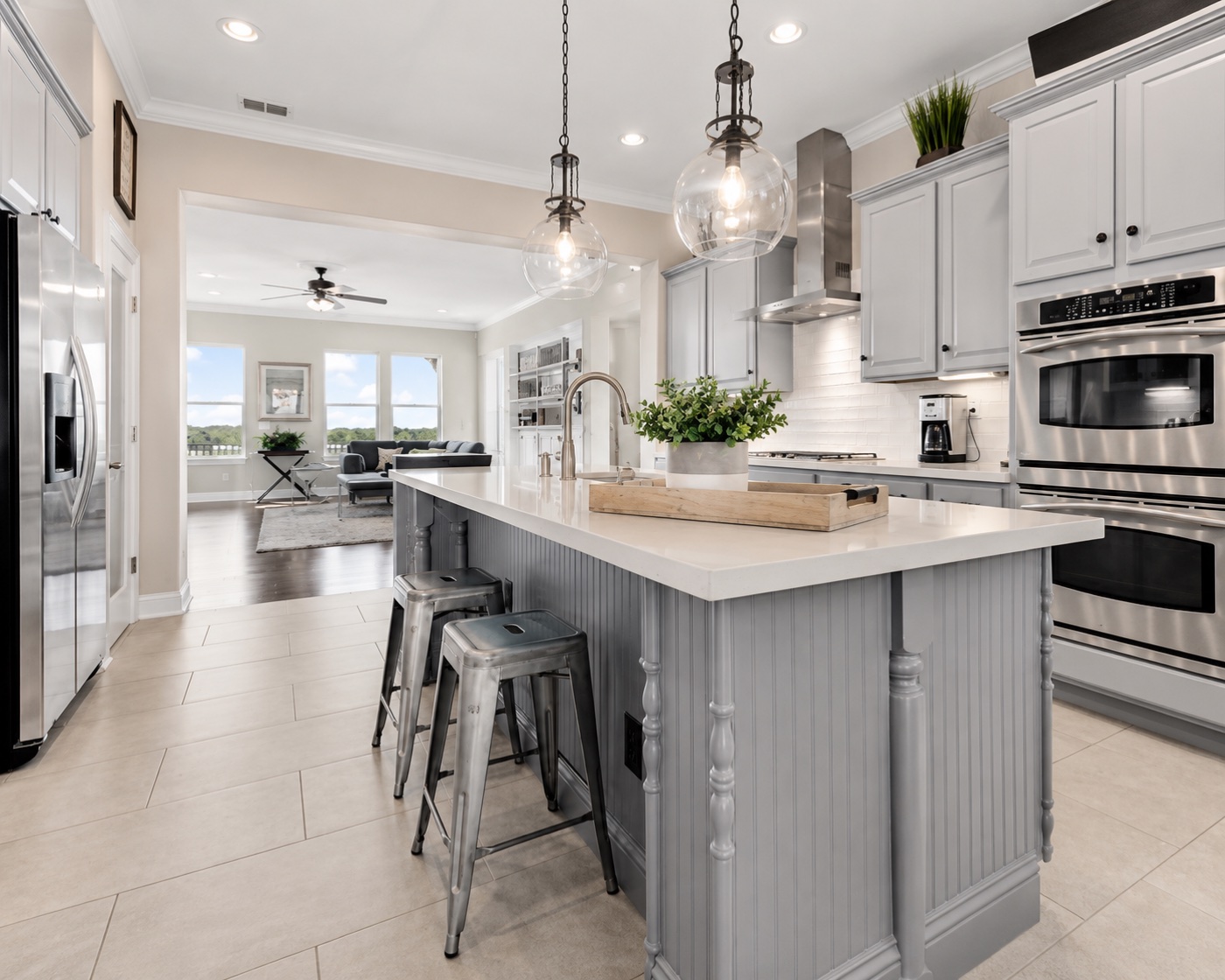 Kitchen island with gray beadboard, pendant lighting, and view into sitting room
