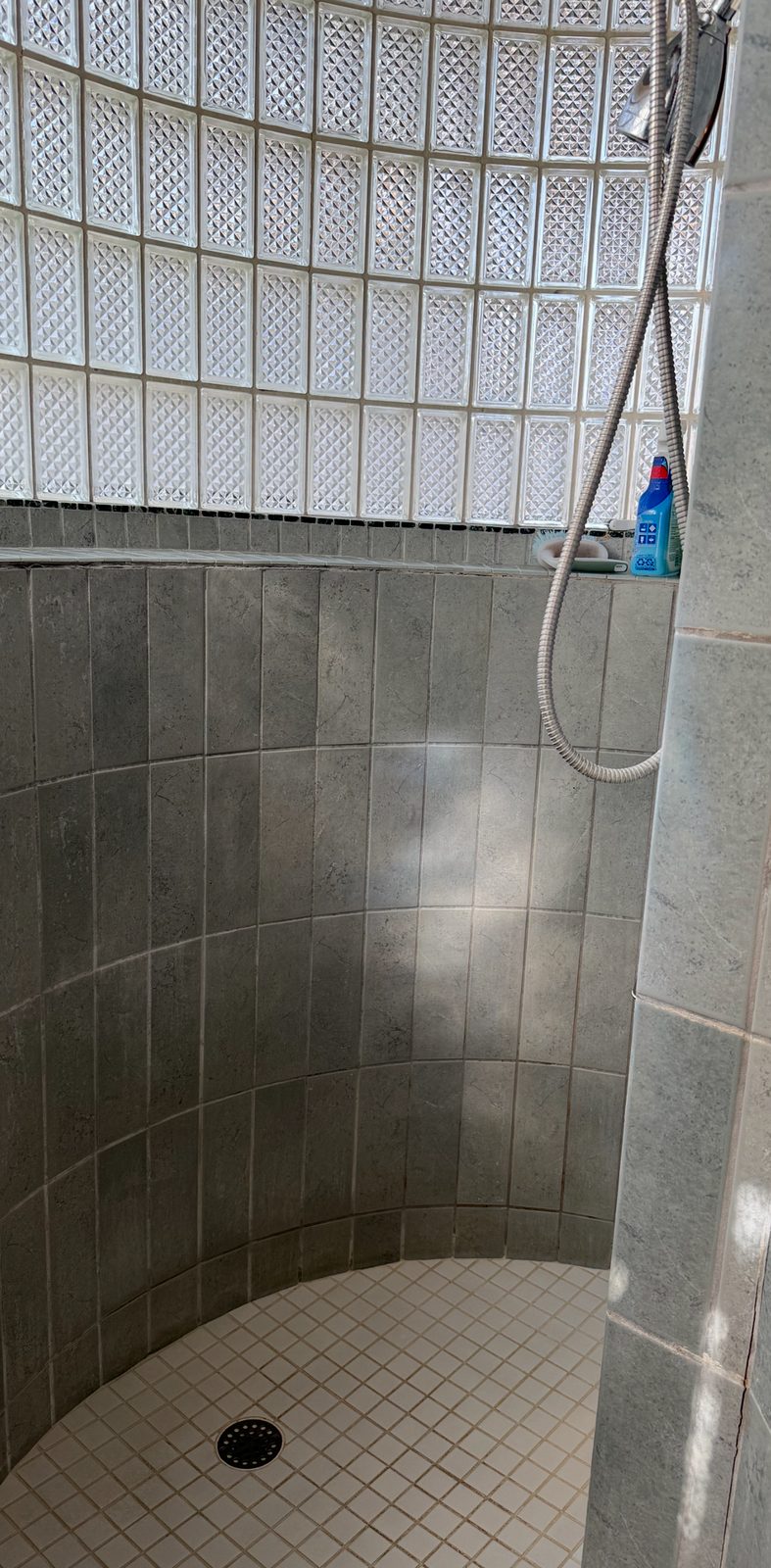 Southlake shower before renovation, with gray tile and a curved glass-block wall