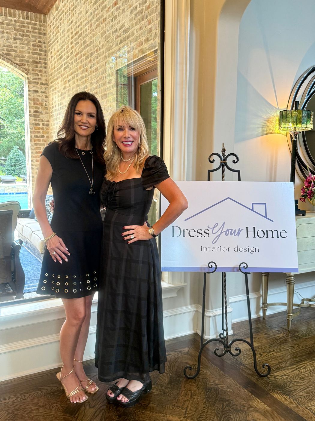 Jenn Robbins and Veronica Eckhardt beside the Dress Your Home interior design sign at the studio launch party